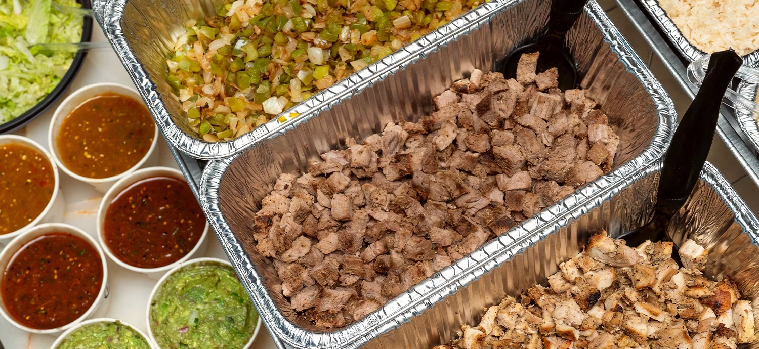 Trays of taco cart meats, rice, beans, salsas and chips